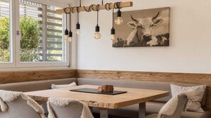 Un coin repas avec une table en bois, des chaises rembourrées et un luminaire suspendu.
