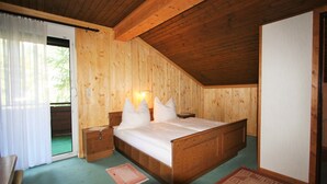 Une chambre aux murs lambrés, avec un lit, des tables de chevet et une fenêtre avec des rideaux.