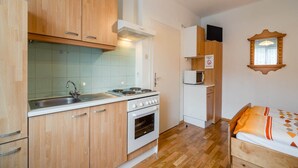 A compact kitchen with wooden cabinets, a sink, a stove, and a microwave. - Holiday apartment in Tröpolach (Tröpolach)