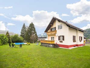 Ein zweistöckiges Haus mit Balkon, Schwimmbad und gepflegtem Rasen.