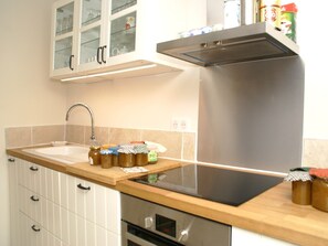 A kitchen with a stainless steel range hood, a sink, and a countertop with jars.