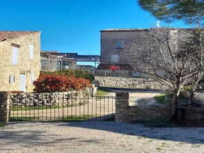 A stone building with a gravel driveway and a metal gate.