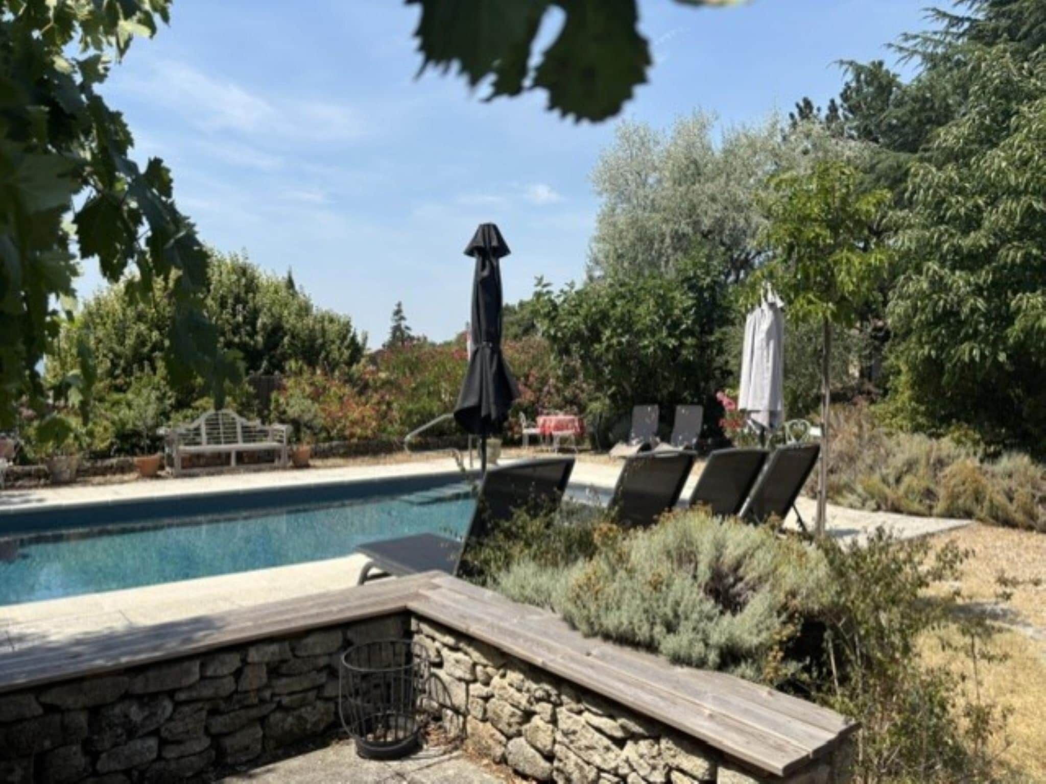 A swimming pool with lounge chairs and a stone wall.