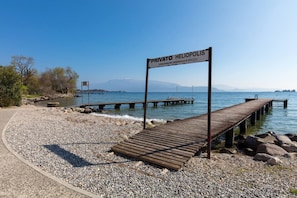A wooden dock extending into a lake with a sign reading "Privato Helipolis".