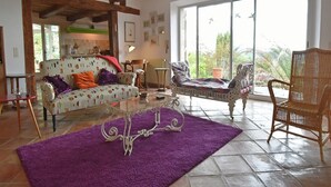 A spacious living room with a large window, a sofa, a chair, and a coffee table.