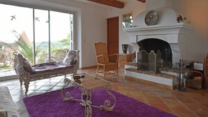 A spacious living room with a fireplace, a large window with a view, and a purple rug.
