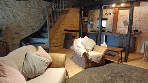 A rustic interior with a stone wall, wooden staircase, and a cozy seating area with a table. - Peaceful Getaway in Teilhet (Teilhet)