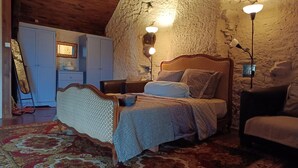 A bedroom with a wooden bed, a nightstand, a dresser, and a stone wall. - Peaceful Getaway in Teilhet (Teilhet)