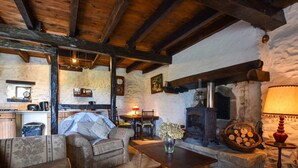 A rustic interior with exposed wooden beams, a stone fireplace, a wooden table, and a cozy seating area. - Peaceful Getaway in Teilhet (Teilhet)