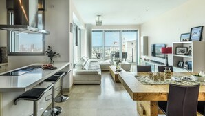 Una cocina moderna con una isla central, taburetes de bar y un comedor con una mesa y sillas de madera.