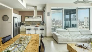 Una cocina moderna con una isla central, un comedor con mesa de madera y un ventanal que ofrece vistas a la ciudad.
