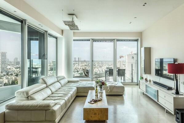 A modern living room with a large sofa, a coffee table, and a TV.