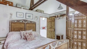 A bedroom with a wooden bed, a wooden door, and a hanging light fixture. - Cottage in Saint-Clair-sur-l'Elle (Saint-Clair-sur-l'Elle)
