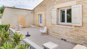 A stone building with a tiled patio, white furniture, and a view of the surrounding landscape. - Holiday home with private pool near Orange (Lagarde-Paréol)