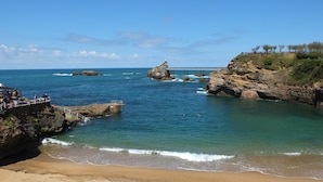A beach with clear blue water, rocky outcrops, and a bridge in the distance. - Villa in France near Beach & Private Pool (Anglet)