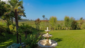 A garden with a central fountain, surrounded by various plants and trees. - Villa in France near Beach & Private Pool (Anglet)