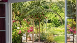 A view of a garden with a wooden pergola, lush greenery, and flowering plants. - Villa in France near Beach & Private Pool (Anglet)