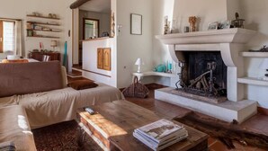 Una sala de estar acogedora con chimenea, un sofá, una mesa de centro con revistas y una estantería.