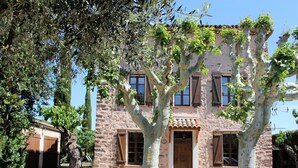 A stone building with a tiled roof, wooden shutters, and a central wooden door. - Private Pool in Provence (La Motte)