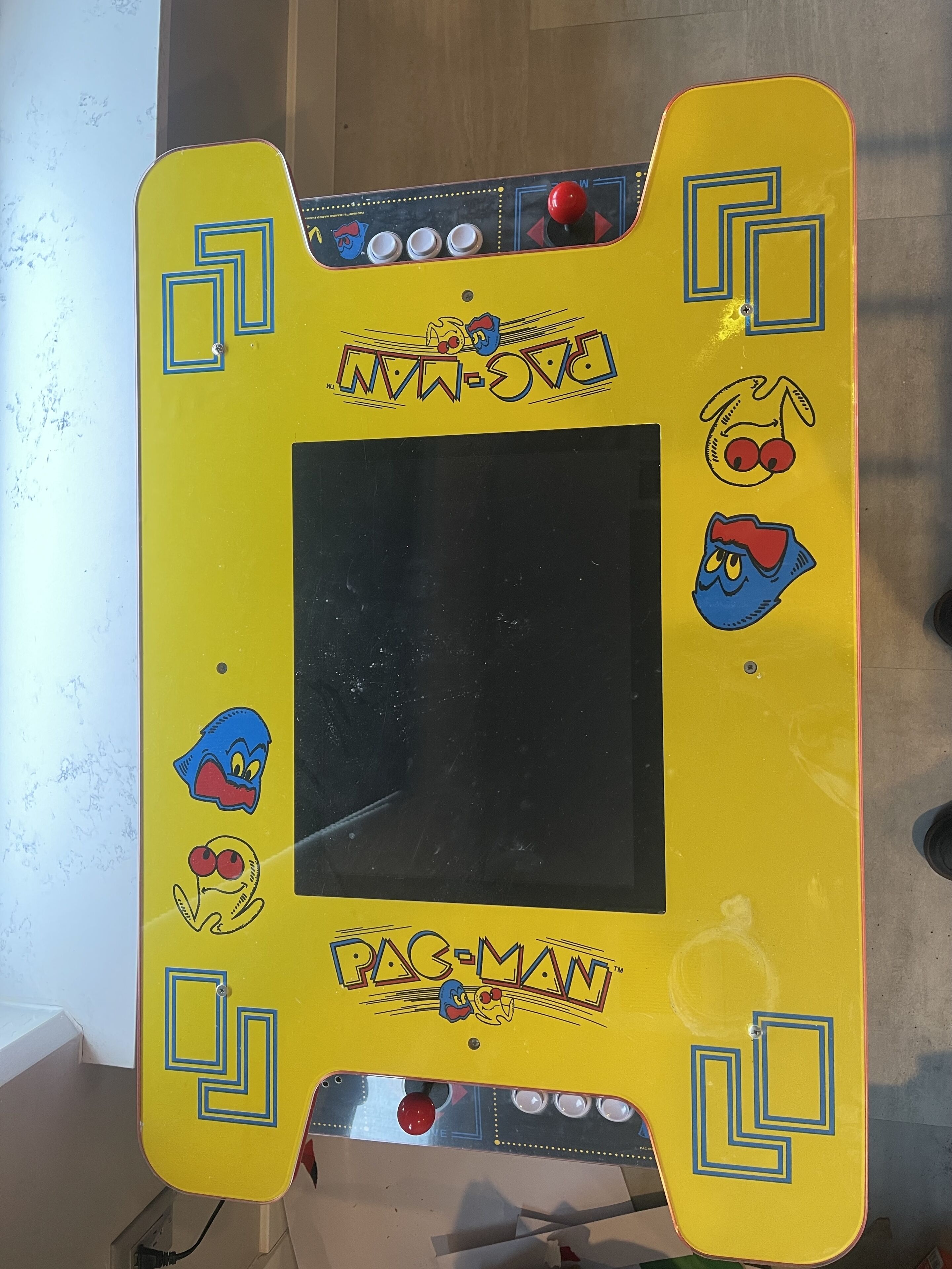Une borne d’arcade jaune avec des personnages de Pac-Man et un joystick.