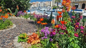 A marina with boats, a waterfront promenade with colorful flowers, and historic buildings in the background. - Spacious villa with heated pool and EV charger (Castelnau d'Aude)