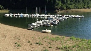 A marina with boats docked along the shore, surrounded by a forested area. - Poolside Bliss Near Lake (Beaulieu)