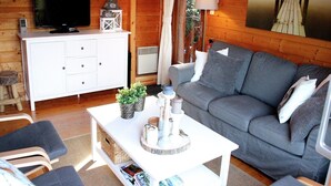 A cozy living room with a grey sofa, white entertainment unit, and a wooden floor. - Poolside Bliss Near Lake (Beaulieu)