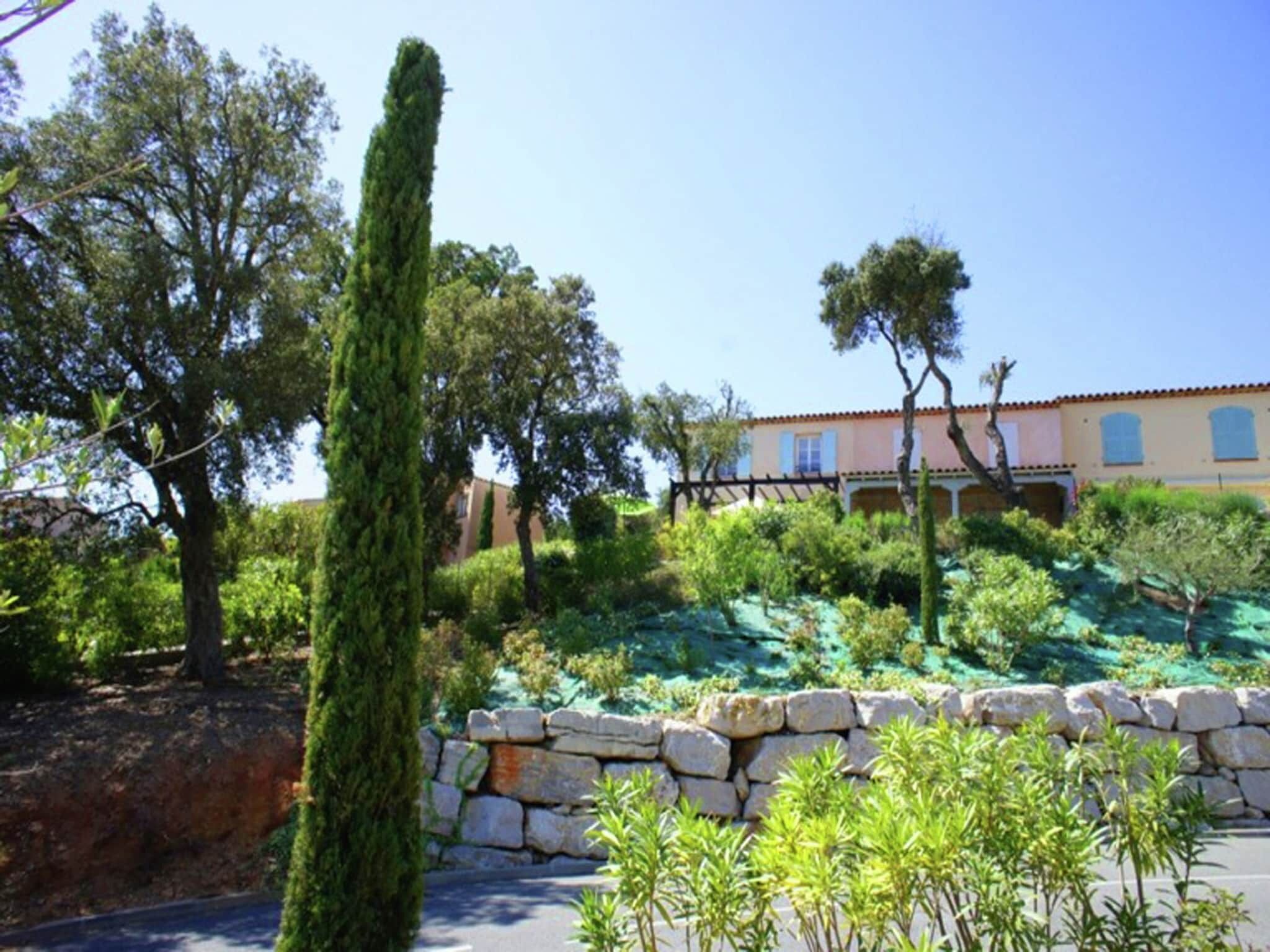A Mediterranean-style building with a stone wall and lush greenery.