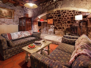 Un salon chaleureux avec des murs en pierre, une cheminée et un mobilier de style traditionnel.