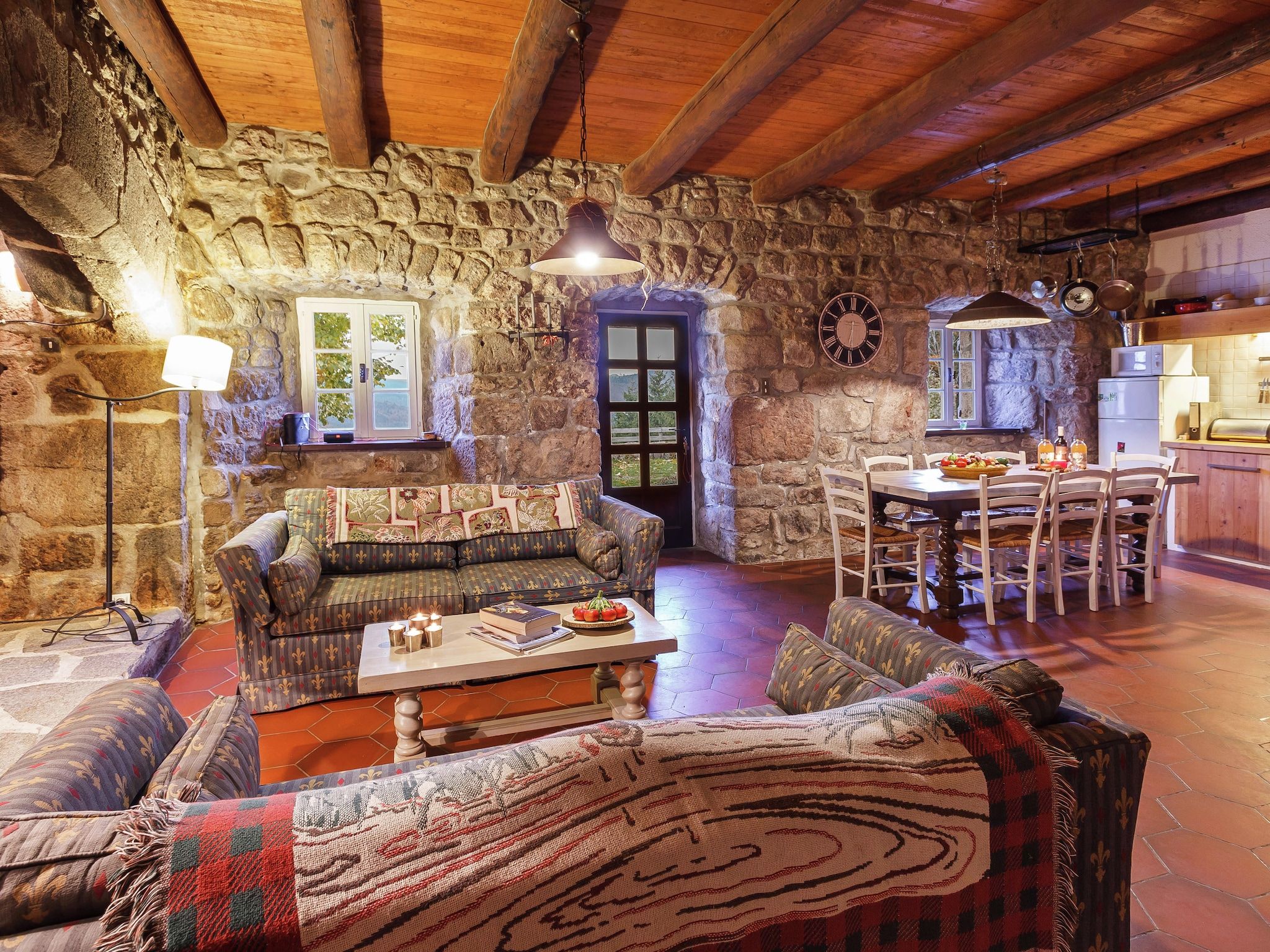 A rustic stone interior with a sofa, dining table, and kitchen area.