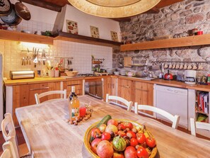 Une cuisine avec des meubles en bois, une table à manger avec des chaises et un mur en pierre.