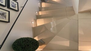 Un intérieur moderne avec un escalier, des photographies encadrées accrochées aux murs et une petite plante verte.