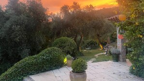 Un jardin avec un sentier en pierre, des plantes en pot et une vue sur le coucher de soleil.