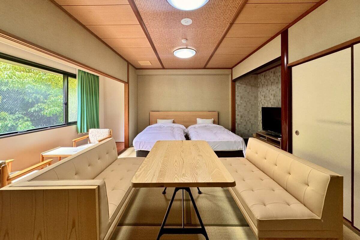 Una habitación con cama, sofá, mesa y televisor.