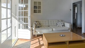 Un salon avec un canapé blanc, une table basse en bois et une grande fenêtre à carreaux.