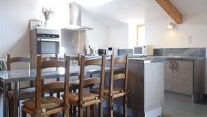 Una cocina moderna con una isla central, sillas de madera, horno empotrado y campana extractora de acero inoxidable.