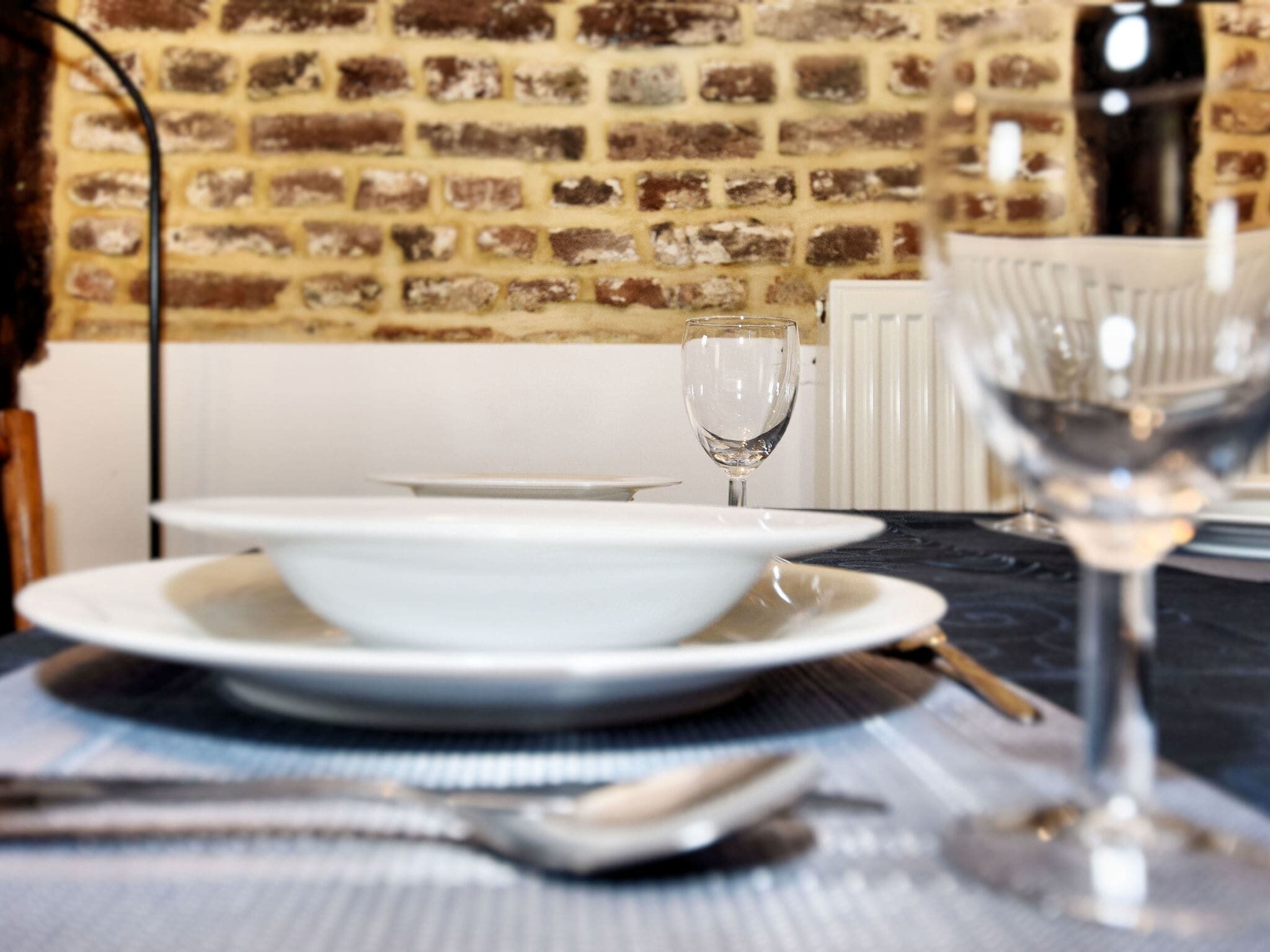 A dining table with a white plate, a wine glass, and a fork.