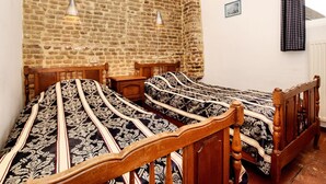 A bedroom with two wooden beds, a brick wall, and a window with curtains. - Lovely Holiday Home in Richelle with Barbecue (Richelle)