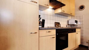 A kitchen with light wood cabinets, a black dishwasher, and a microwave on the countertop. - Lovely Holiday Home in Richelle with Barbecue (Richelle)