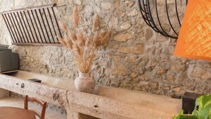 A stone wall with a rustic bench, a vase with dried pampas grass, and a wooden table with chairs. - Cottage in Montbrun-des-Corbières (Montbrun des Corbières)