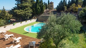 A pool area with a wooden deck, lounge chairs, and a small garden with a tree and potted plants. - Cottage in Montbrun-des-Corbières (Montbrun des Corbières)