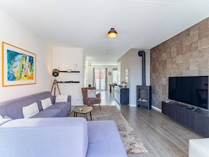 A modern living room with a grey sofa, a coffee table, a chair, a painting on the wall, a fireplace, and a TV.