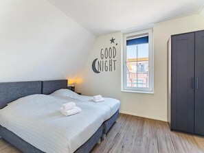 Een slaapkamer met een bed, een kledingkast, een raam met uitzicht en een wanddecoratie met de tekst 'GOOD NIGHT'.