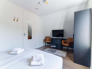 Quarto de hotel moderno com duas camas, uma televisão, uma escrivaninha e um guarda-roupa.