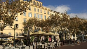 An outdoor cafe area with tables and chairs, surrounded by trees and a building with multiple windows. - Apartment in Corsica near Beaches (Poggio Mezzana)