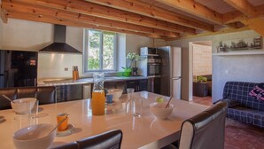 A modern kitchen with wooden beams, a dining area with a table set for two, and a living area with a sofa. - Apartment in Corsica near Beaches (Poggio Mezzana)