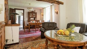 Una sala de estar con una mesa redonda, un sofá de cuero y un comedor con una mesa y sillas de madera.
