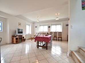 A spacious living room with a dining area, a television, and a radiator. - Home for 7 Guests in Plouvara (Plouvara)