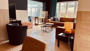 Een moderne woonkamer met een bank, fauteuil, salontafel en een televisie.