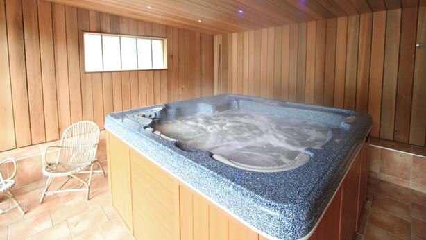 A spa room with a hot tub, wooden walls, and a window. - Holiday Home in Borgoumont near Spa Town (La Gleize)